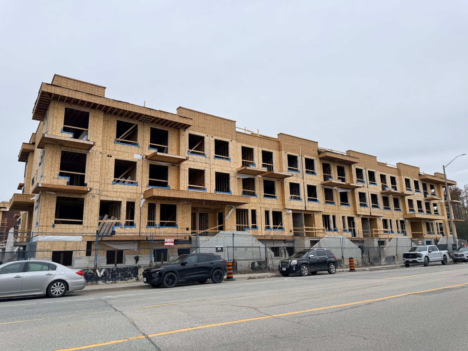 A GTA buyer reviewing new construction purchase documents at a table with a new home development visible through the window