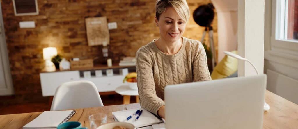 Brampton home buyer reviewing economic indicators on laptop at kitchen table with housing market notes