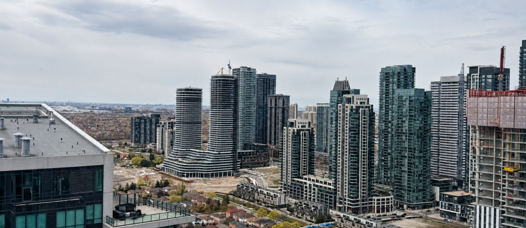 A couple reviewing condo purchase documents at a kitchen table with a city view through the window in Etobicoke