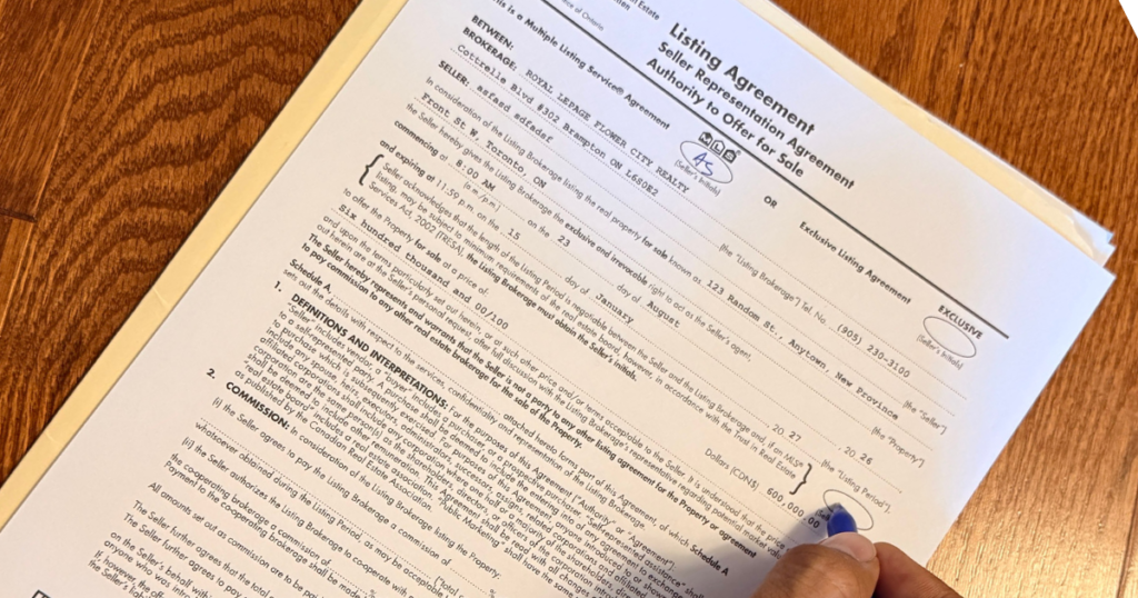 Close-up of a hand signing an Ontario Listing Agreement (Seller Representation Agreement) with a blue pen on a wooden desk