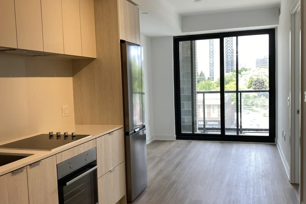 Narrow open-plan kitchen and living area with wood cabinetry, built-in appliances and sliding glass balcony doors.